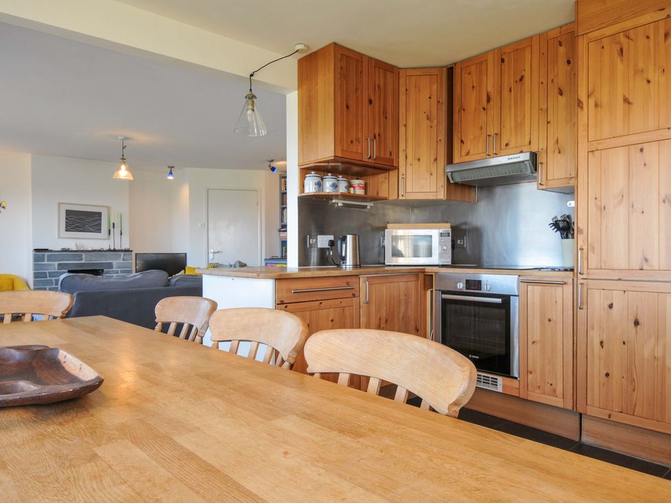 A kitchen with wooden cabinets and a dining table at Upper Gren in Trebetherick
