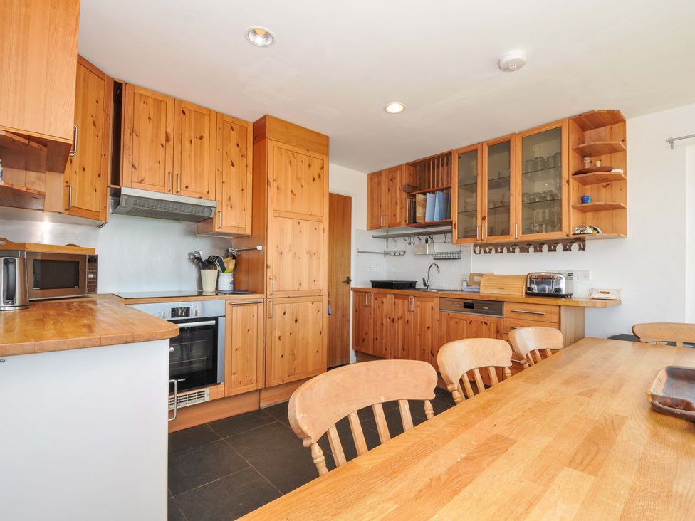 A kitchen with wooden cabinets and table at Upper Gren in Trebetherick