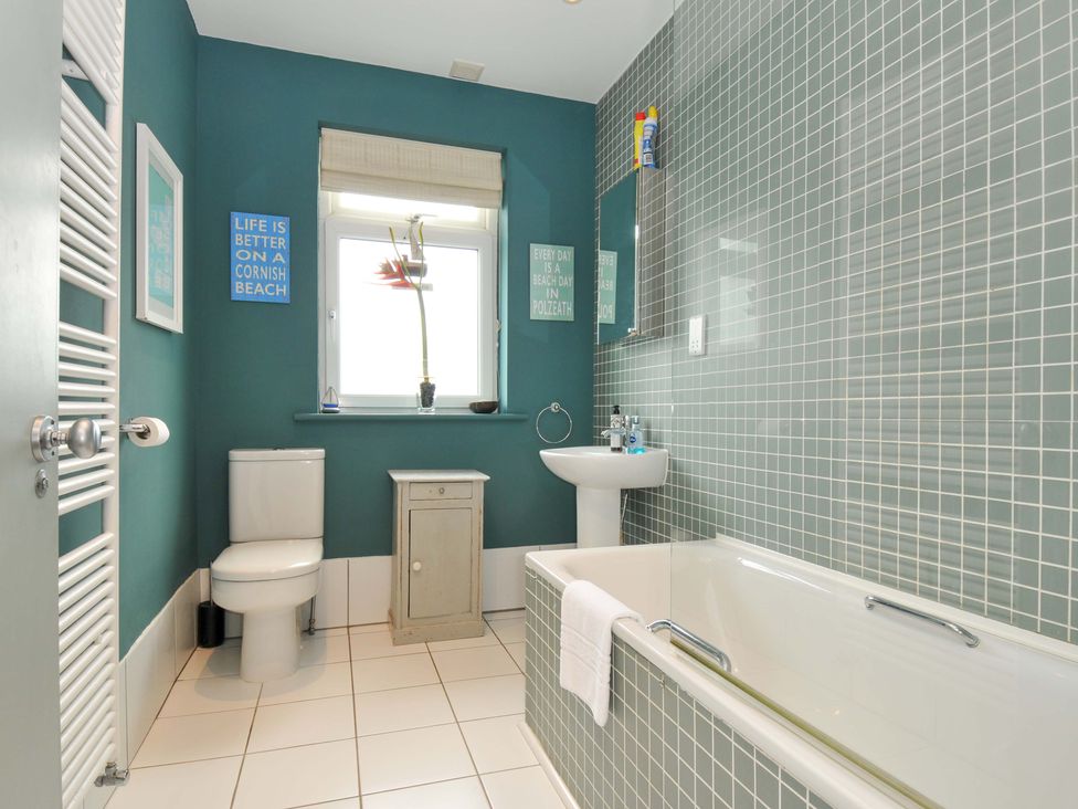 A bathroom featuring a bathtub, toilet, sink, and window at The Point in Polzeath