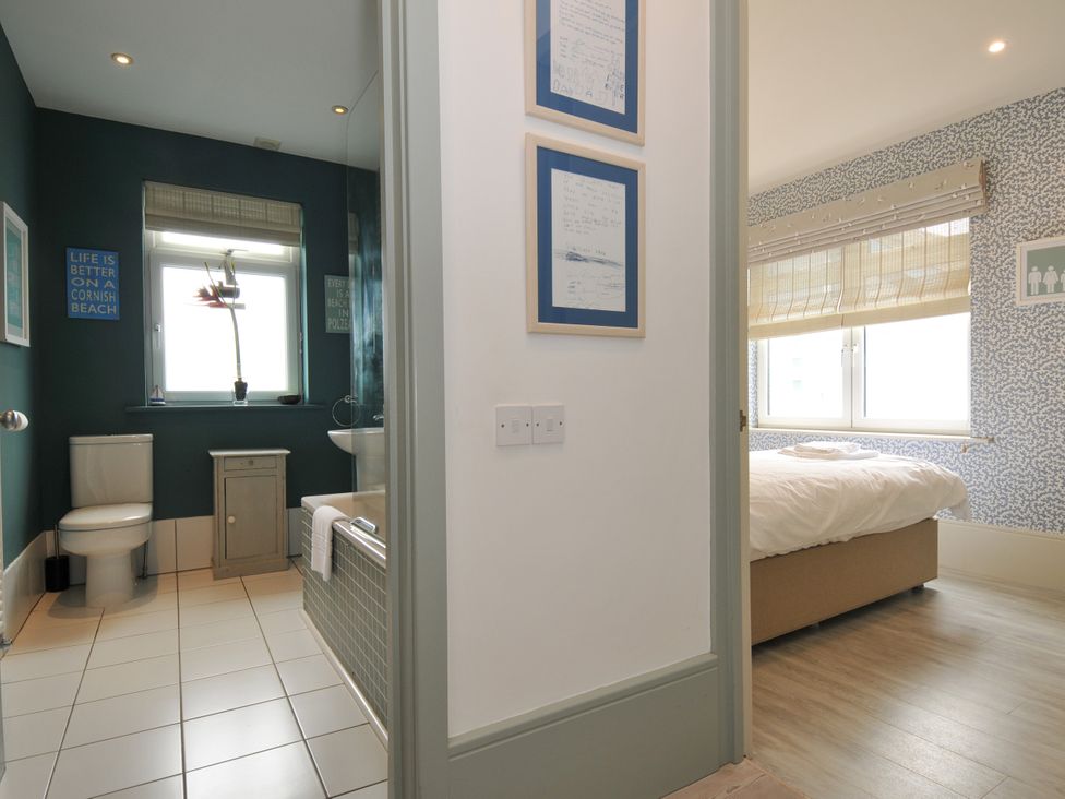 A bathroom with a toilet and bathtub connected to a bedroom at The Point in Polzeath