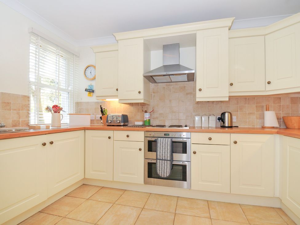 A kitchen with cream cabinets wooden countertops tiled backsplash and floor at Lowenna Manor 3 in Rock