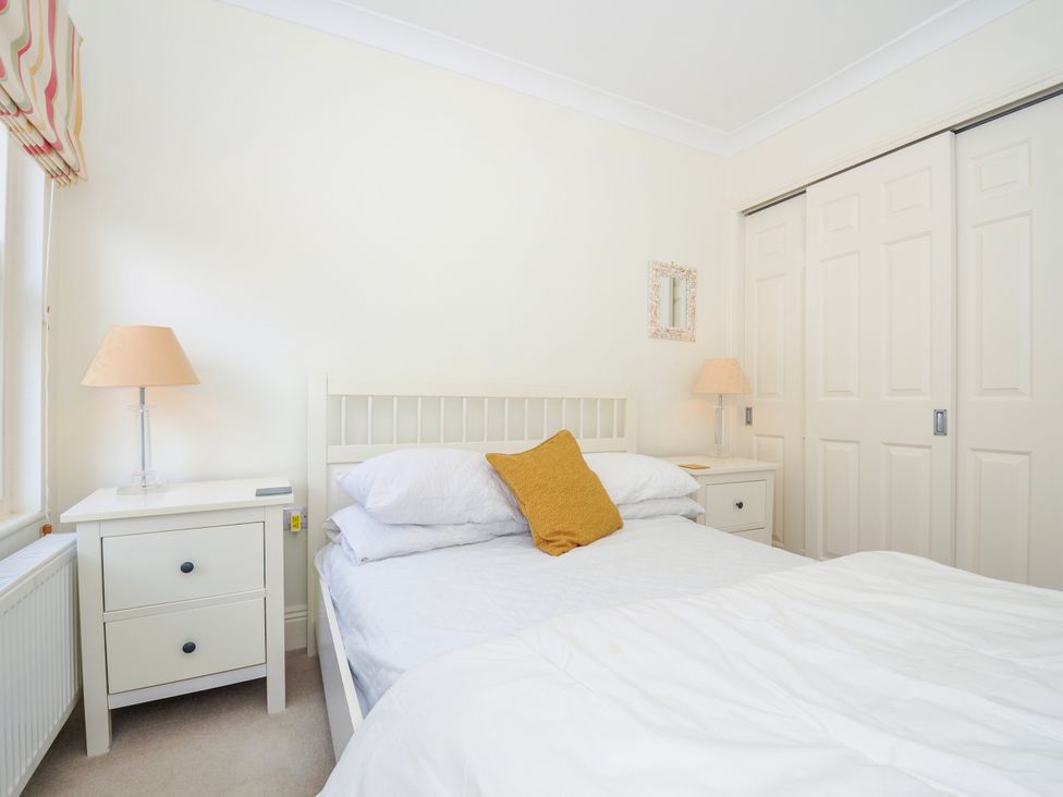A bedroom with a white bed, bedside tables with lamps, and built-in wardrobes at Lowenna Manor 3 Rock