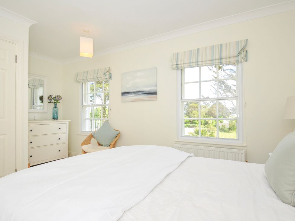 A bedroom with a bed a chest of drawers a chair two windows and a painting at Lowenna Manor 3 Rock