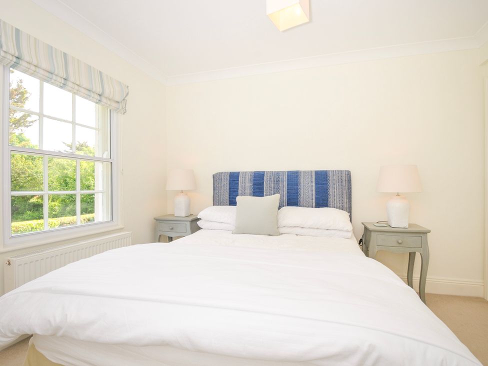 A bedroom with a bed with blue headboard and white bedding between two bedside tables with lamps Lowenna Manor 3 Rock