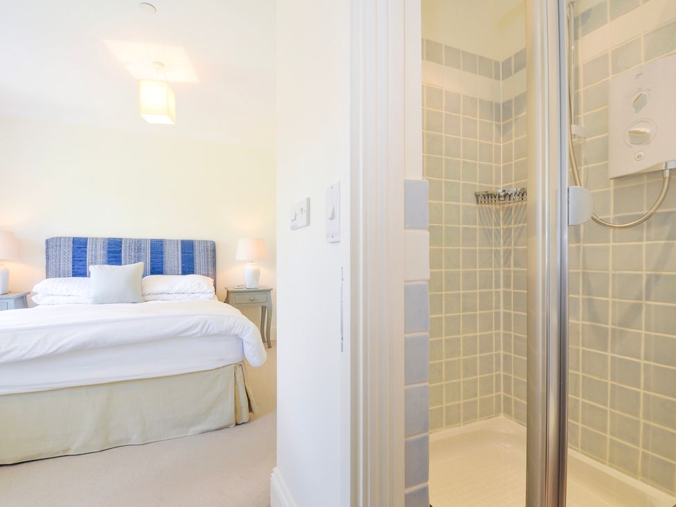 A bedroom with a bed and lamps next to an open shower with tiled walls at Lowenna Manor 3 in Rock