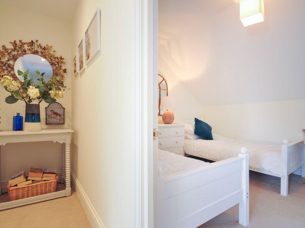 A hallway with a table holding flowers and a mirror next to a bedroom with two beds and a nightstand at Lowenna Manor 3 in Rock