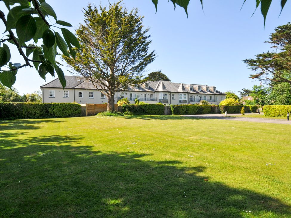 A large lawn with trees and hedges in front of a two story building at Lowenna Manor 3 in Rock