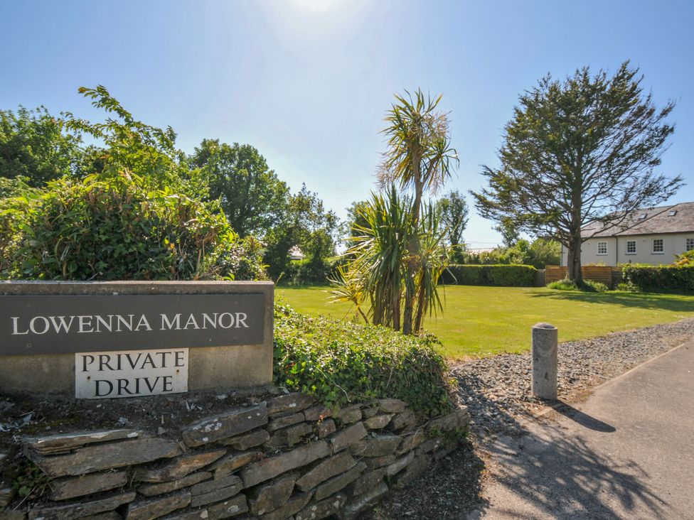 A driveway entrance with a sign reading Lowenna Manor private drive a lawn with trees and a house in the background at Lowenna Manor 3 Rock