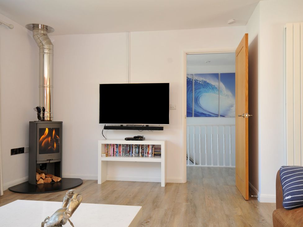 A living room with a fireplace and television at Beaches in Polzeath