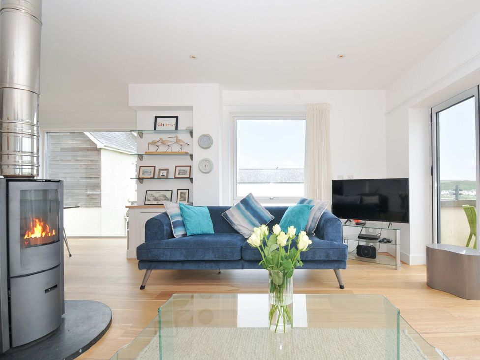 A living room with a fireplace and sofa at Stepper Point in Polzeath
