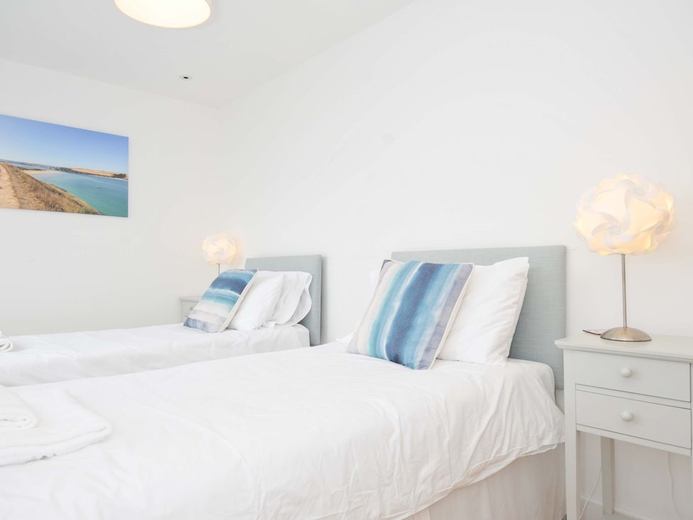 A bedroom with two single beds and a nightstand at Stepper Point in Polzeath