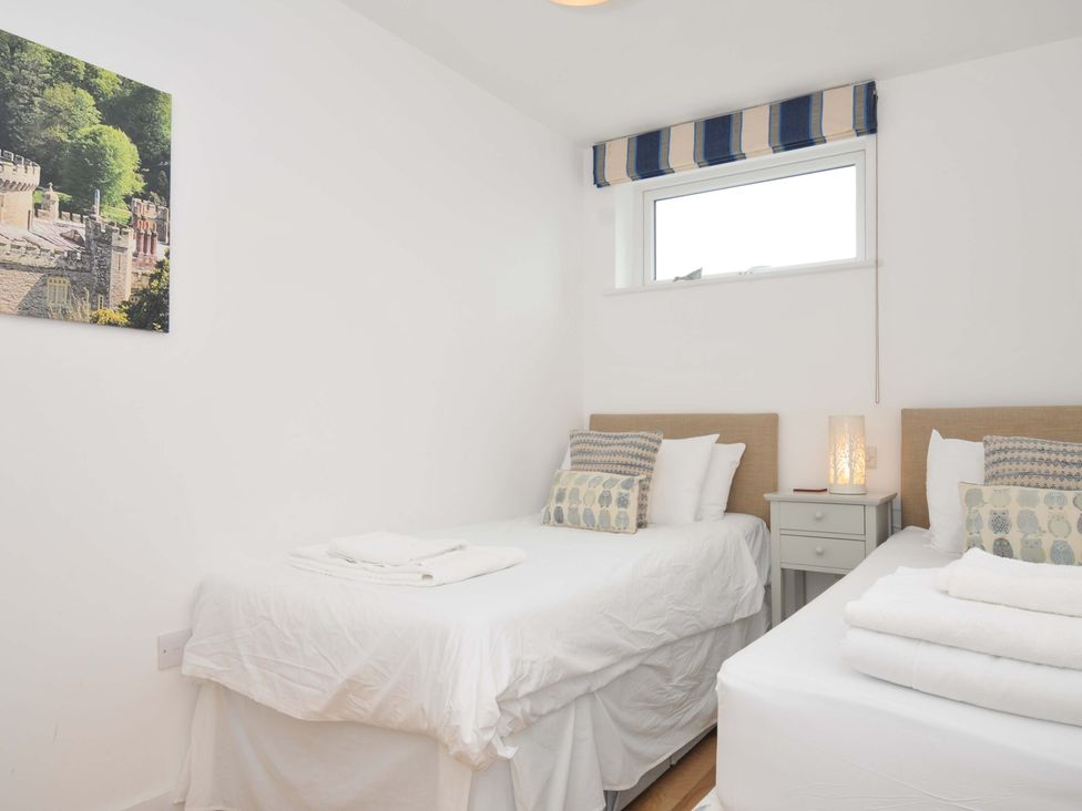 A bedroom with two beds and a bedside table at Stepper Point in Polzeath