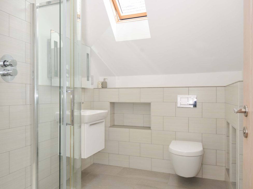 A bathroom with a shower, toilet, and sink at Stepper Point in Polzeath