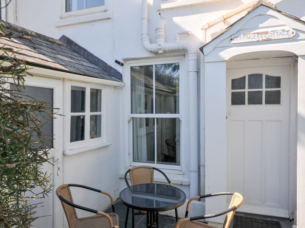 An outdoor area with a table and chairs at Coppingers Cottage in Polzeath