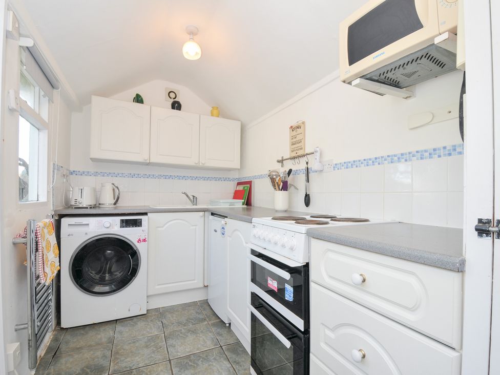 A kitchen with a washing machine and stove at Coppingers Cottage Polzeath
