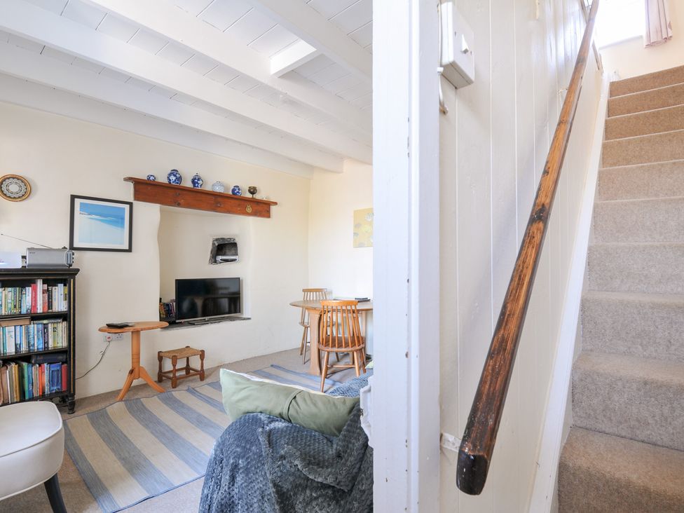 A living room with a bookshelf and TV at Coppingers Cottage in Polzeath