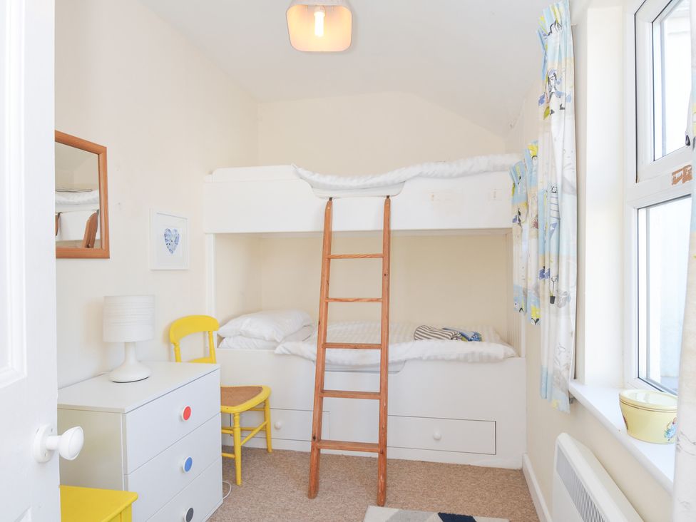 A bedroom with a bunk bed and a ladder at Coppingers Cottage in Polzeath