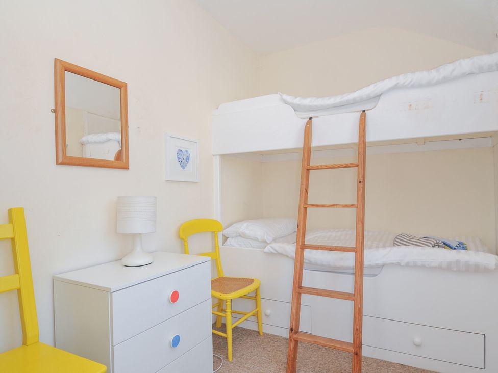 A bedroom with a bunk bed and a lamp at Coppingers Cottage Polzeath