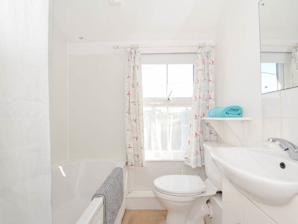 A bathroom with a bathtub, toilet, and sink at Coppingers Cottage in Polzeath