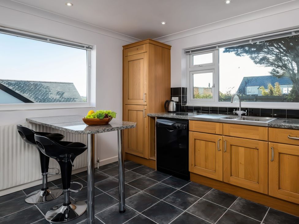 A kitchen with a granite counter and stools at Hillview in Polzeath