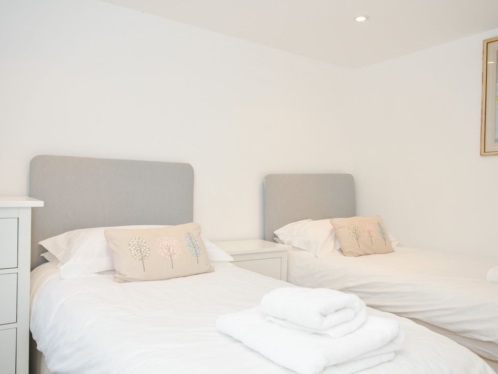 A bedroom with two beds and a bedside table at Orchard Cottage Polzeath