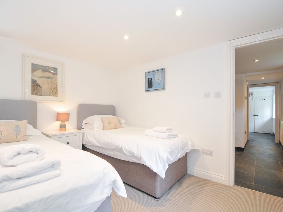 A bedroom with twin beds and a painting at Orchard Cottage in Polzeath