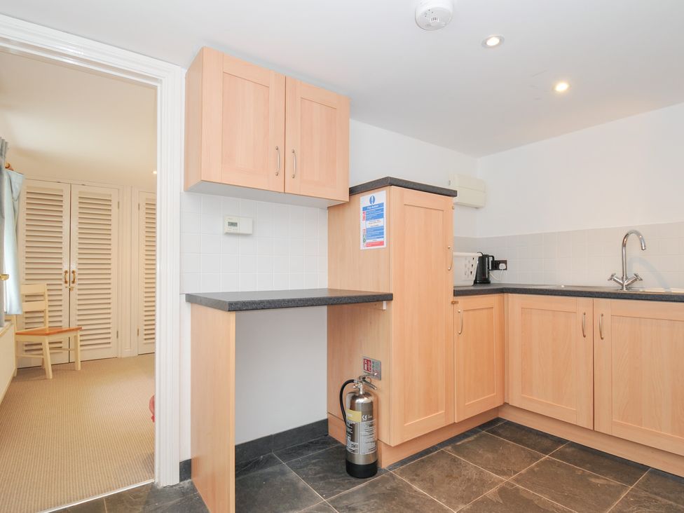 A kitchen with cabinets and a sink at Orchard Cottage in Polzeath