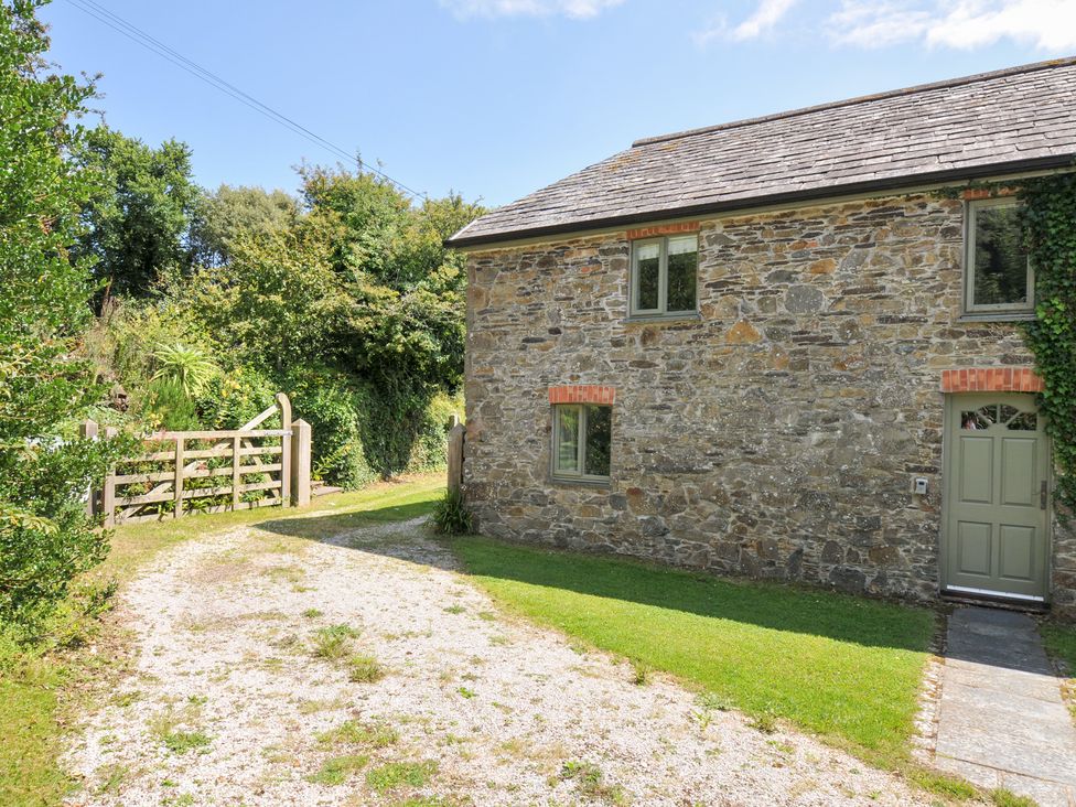 A stone building with windows and a gate at Orchard Cottage in Polzeath
