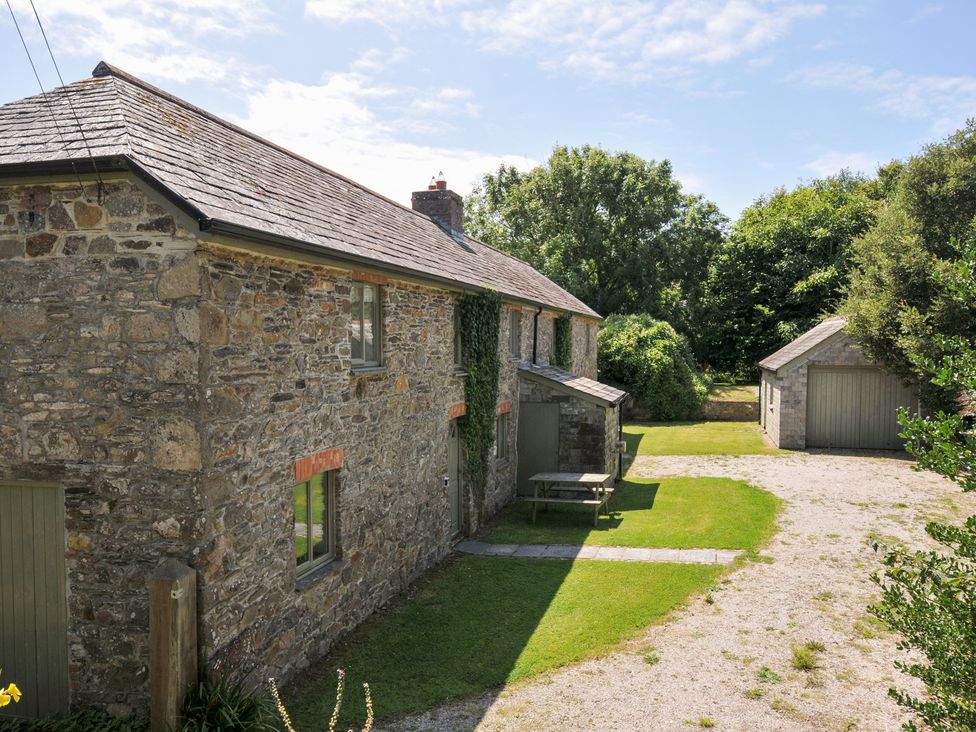 An outdoor view of a stone house and garage at Orchard Cottage in Polzeath