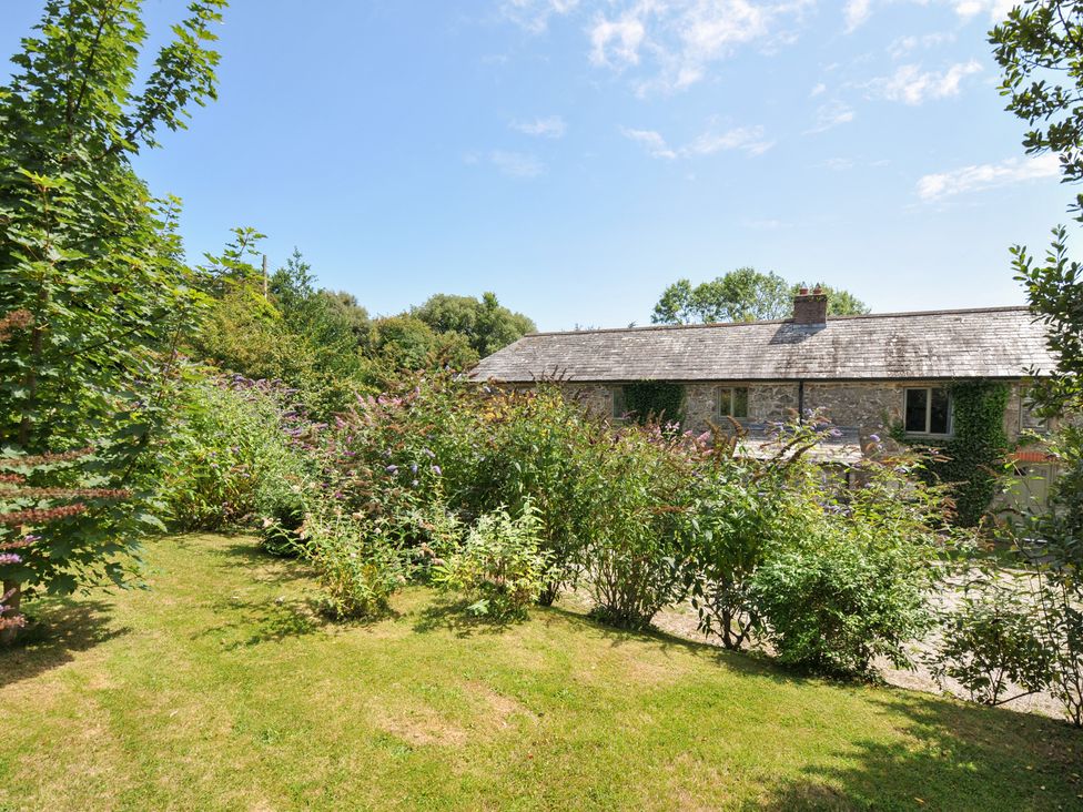A garden with a house and greenery at Orchard Cottage in Polzeath
