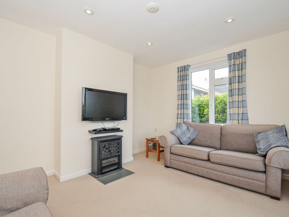 A living room with a television and a fireplace at Hillcroft Bungalow Daymer Bay