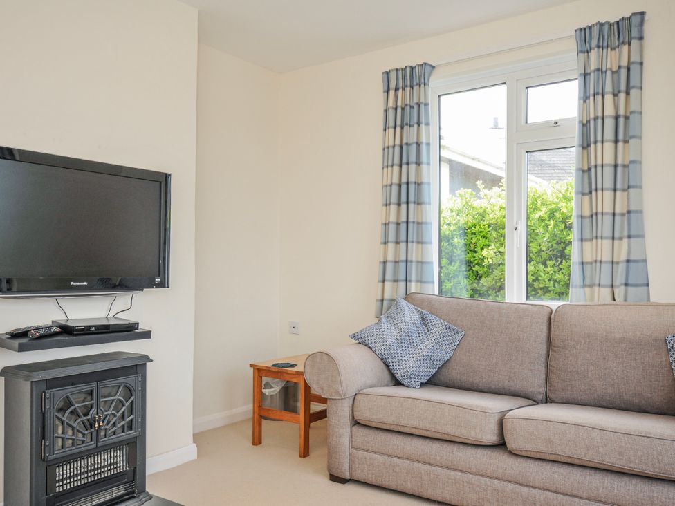 A living room with a television and sofa at Hillcroft Bungalow in Daymer Bay