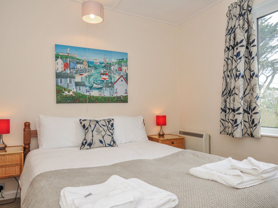 A bedroom with a double bed and wall art at Hillcroft Bungalow Daymer Bay