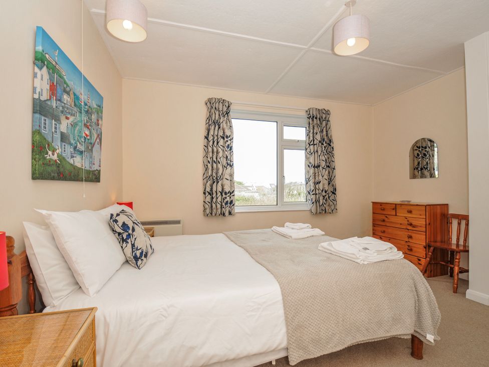 A bedroom with a bed and window at Hillcroft Bungalow Daymer Bay