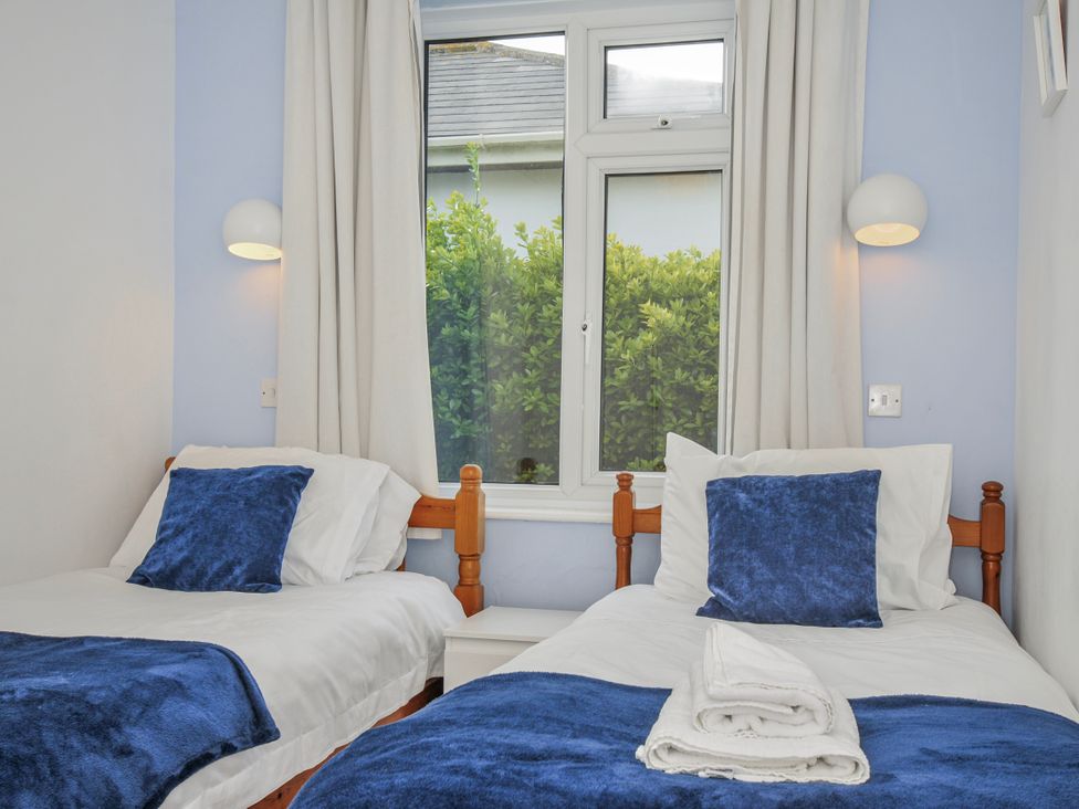 A bedroom with two beds and a window at Hillcroft Bungalow Daymer Bay
