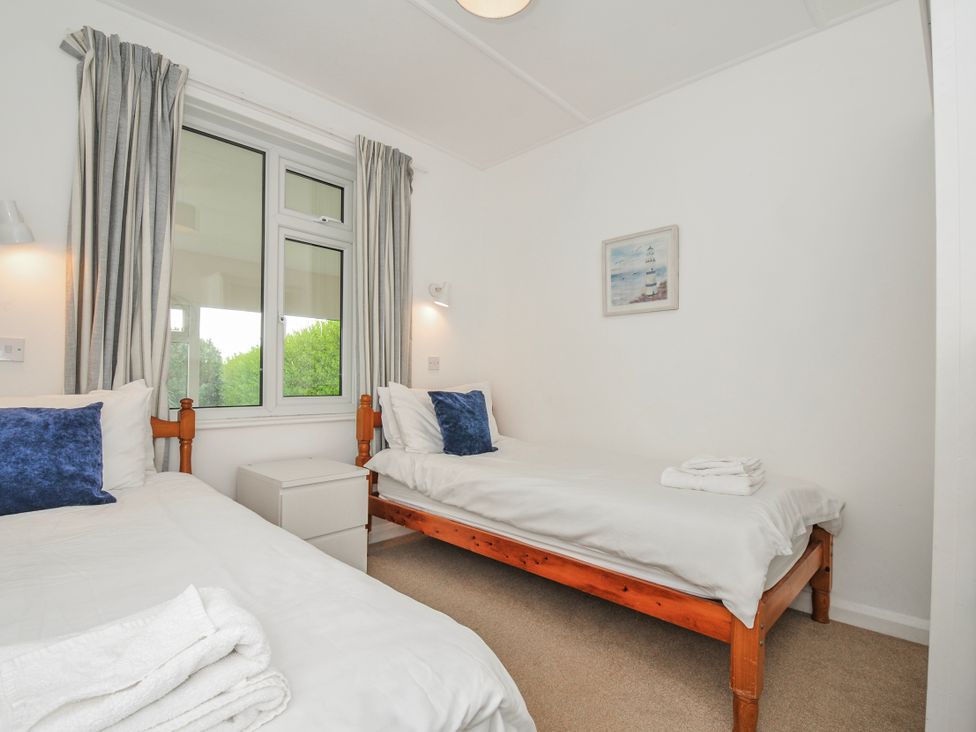 A bedroom with two beds and a window at Hillcroft Bungalow Daymer Bay