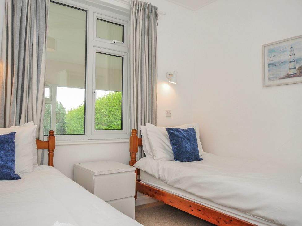 A bedroom with two single beds and a window at Hillcroft Bungalow Daymer Bay
