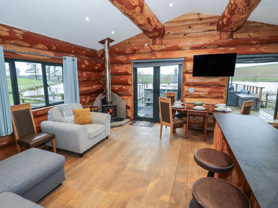 A living room with a sofa and dining area at Cedar Cabin at Salford Court Farm Fishing Cabins near Clifton Upon Teme