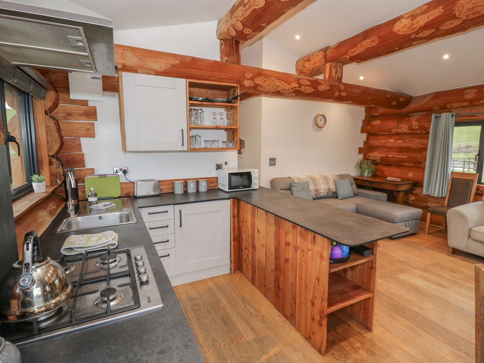 A kitchen with wooden cabinets and a seating area at Cedar Cabin at Salford Court Farm Fishing Cabins Near Clifton Upon Teme