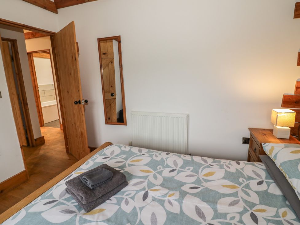 A bedroom with a bed and a door leading to a bathroom at Cedar Cabin at Salford Court Farm Fishing Cabins near Clifton Upon Teme