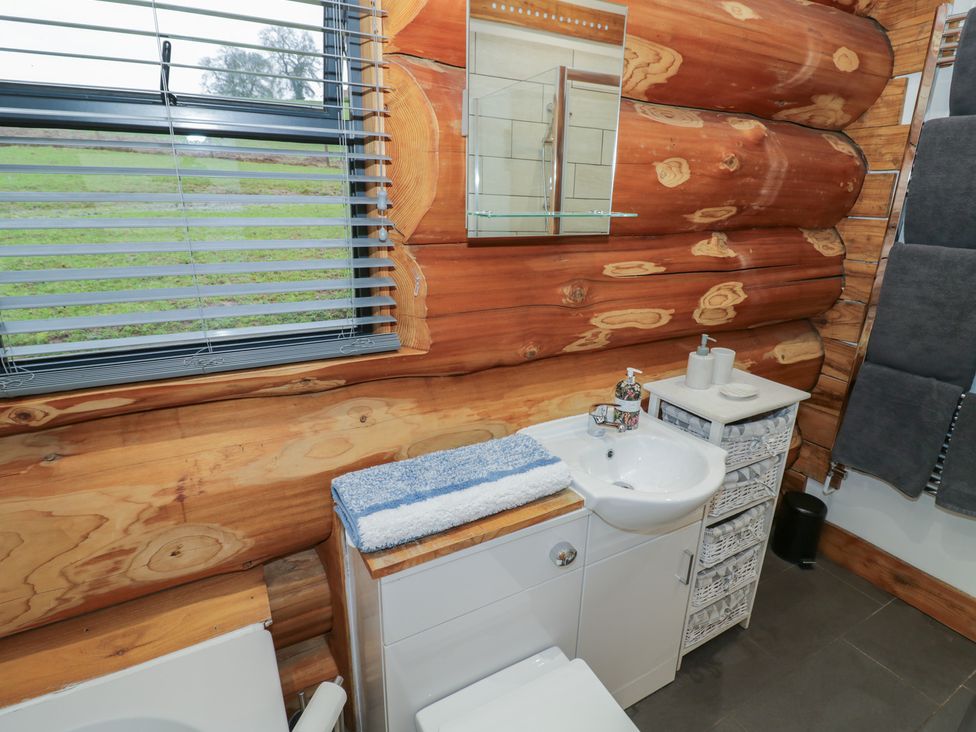 A bathroom with wooden wall and sink at Cedar Cabin at Salford Court Farm Fishing Cabins near Clifton Upon Teme
