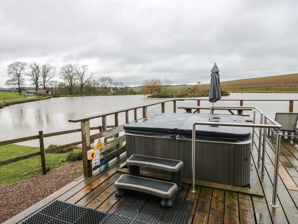 An outdoor area with a hot tub and views of the lake at Cedar Cabin at Salford Court Farm Fishing Cabins near Clifton Upon Teme