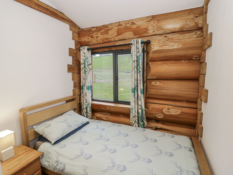 A bedroom with a bed and window at Douglas Cabin at Salford Court Farm Fishing Cabins near Clifton Upon Teme