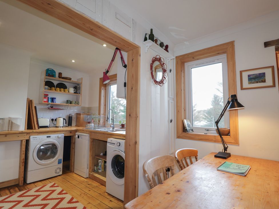 A kitchen with washing machines and a table at Free Presbyterian Manse in Kinlochbervie