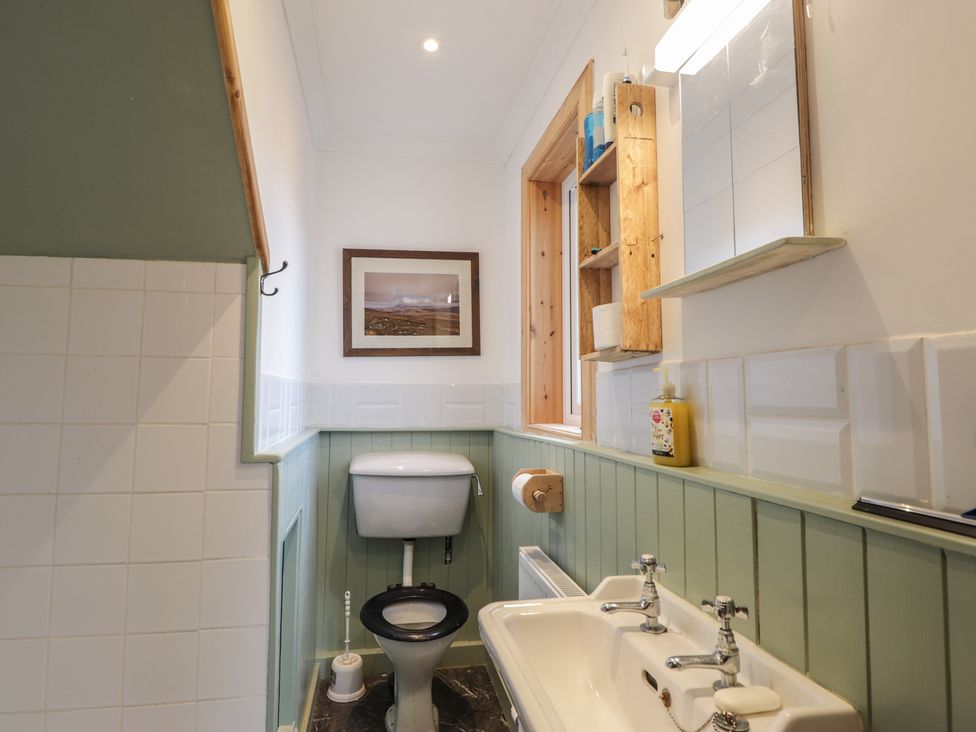 A bathroom with a toilet, sink, and mirror at Free Presbyterian Manse in Kinlochbervie