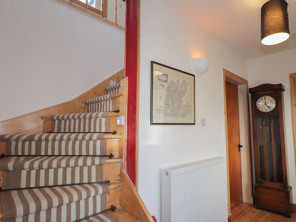 A staircase with a wall clock and a map in the hallway at Free Presbyterian Manse in Kinlochbervie