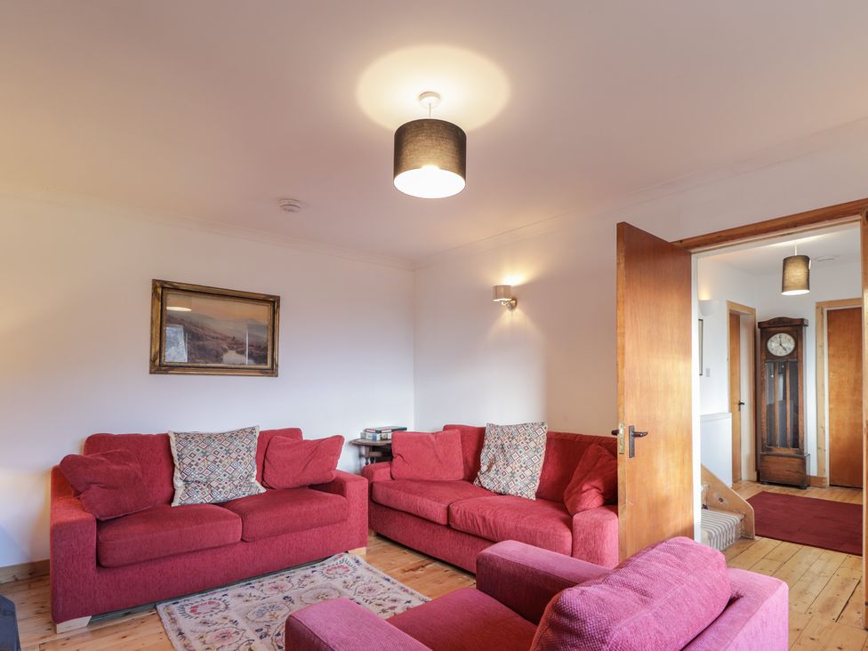 A living room with red sofas and a clock at Free Presbyterian Manse in Kinlochbervie