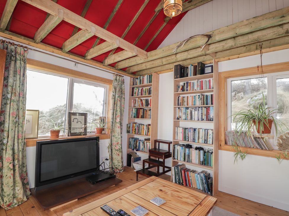 A living room with a television and bookshelves at Free Presbyterian Manse in Kinlochbervie