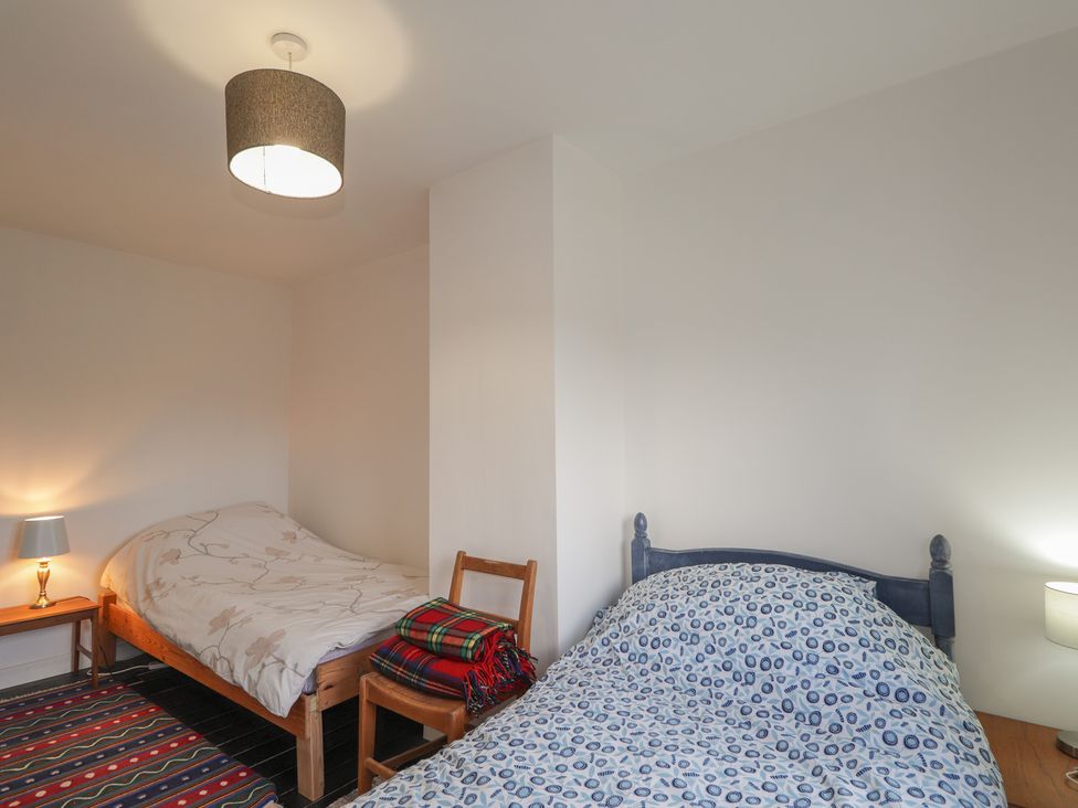 A bedroom with two beds and a bedside table at Free Presbyterian Manse Kinlochbervie