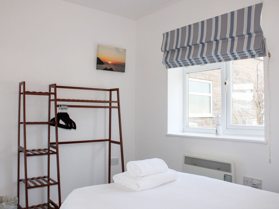 A bedroom with a bed and hanging rack at Gilly's Cottage in Hope Cove